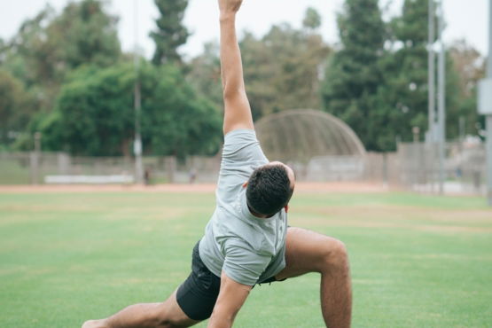 man in black and white t-shirt and black shorts sitting on green grass field during